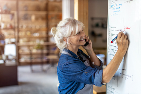 Worker writing on whiteboard while talking on the phone