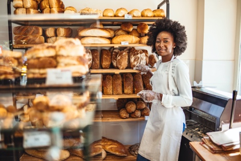 Worker standing in front of shelves of bread 
